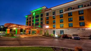 Un hotel con un estacionamiento enfrente. en Holiday Inn & Suites Tupelo North by IHG, en Tupelo