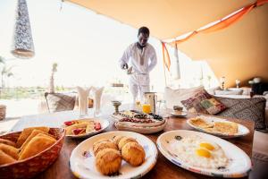 un homme debout devant une table avec des aliments pour le petit-déjeuner dans l'établissement Les Dunes de Dakhla, à Dakhla