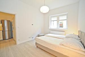 a white bedroom with a bed and a window at Family apartment 50 m from Monte Cassino by Grand Apartments in Sopot