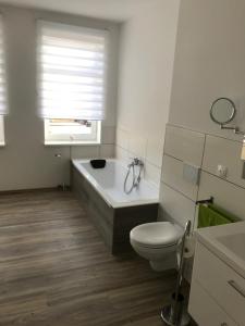 a bathroom with a tub and a toilet and a window at Ferienwohnung Weserbergland Haus Nr 25 in Deensen +7 photos