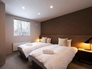 a bedroom with two beds with white sheets and a window at Chalet Ukiyo in Niseko