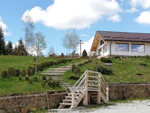 a house with a wooden staircase next to a house at Pensiunea L`Amoro in Neagra Şarului