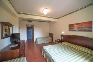 ein Hotelzimmer mit 2 Betten und einem Flachbild-TV in der Unterkunft Orizzonte Acireale Hotel in Acireale