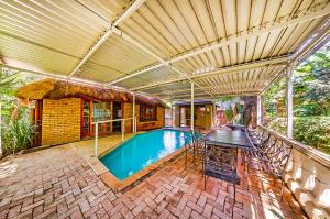 a house with a swimming pool with a table at Amper Bo Guest House in Pretoria
