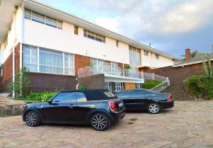 dos autos estacionados en un estacionamiento frente a un edificio en THE WHITE HOUSE, en Johannesburgo