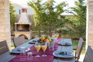 una mesa con vasos de zumo de naranja y una cesta de fruta en Villa Helios, en Spartia