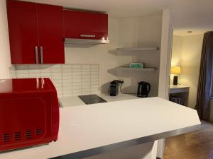 ストラスブールにあるTrès Grand Studio - Strasbourgのキッチン(赤いキャビネット、白いカウンタートップ付)