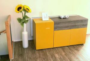 a vase with a sunflower sitting on a yellow cabinet at Gräfin von Paris - Appartement mit Saunanutzung in Burgbernheim +28 photos