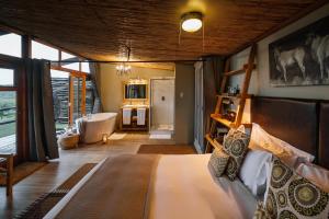 a bedroom with a bed and a bathroom with a tub at Cheetah Ridge Lodge in Nambiti Private Game Reserve