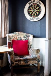 a chair with a red pillow next to a dart board at The Dorset Arms Pub & Cottage Rooms in Groombridge +31 photos