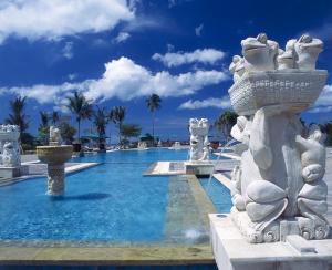 a large swimming pool with a fountain and palm trees at Angsana Bintan in Lagoi