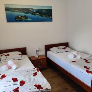twee bedden in een kamer met rode bloemen bij Guest House Šapina in Korenica