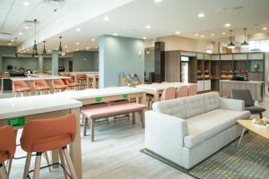 Holiday Inn & Suites Orlando - International Dr S, an IHG Hotel في أورلاندو: غرفة انتظار مع أريكة وطاولات وكراسي