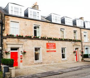 een bakstenen gebouw met een rode deur en bloemen erop bij Balmore Guest House in Edinburgh