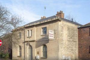 an old brick building with a sign on it at Unique and quirky central apartment with parking in Oxford