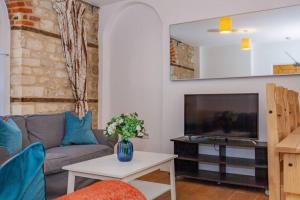 a living room with a couch and a tv at Unique and quirky central apartment with parking in Oxford