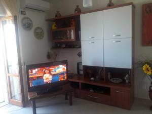 a living room with a television and a large cabinet at Tramonti in San Menaio