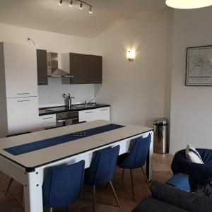 uma cozinha com uma mesa e algumas cadeiras azuis em Suite Mermoz -T3- Belle vue - Billard-wifi-Vélo em Castelnaudary