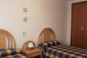 a bedroom with two beds and a table with a lamp at Apartaments Lamoga - Monteixo in Torredembarra