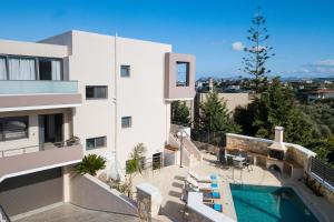 a white building with a swimming pool next to a building at Peris Villa in Kato Daratso