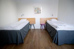 two beds in a room with two chairs at Sunderby folkhögskola Hotell & Konferens in Luleå