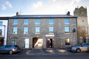 a large brick building with a doorway and cars parked in front at Rooms at the Lower House in Dungannon