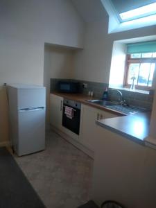 a kitchen with a white refrigerator and a sink at Peak District Apartment in Alsop en le Dale