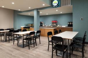 Holiday Inn & Suites Orlando - International Dr S, an IHG Hotel في أورلاندو: غرفة طعام مع طاولات وكراسي ومطبخ