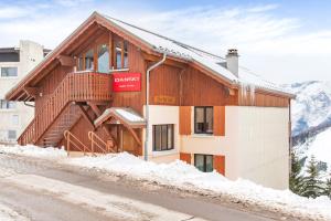 a wooden building with snow on the ground at Chalethotel Belle Etoile in L'Alpe-d'Huez