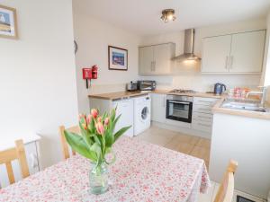 a kitchen with a table with a vase of flowers on it at Castle Cove in Abergele