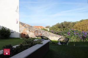 un jardín con 2 sillas y una pared de piedra en Villas de Cintra, en Sintra