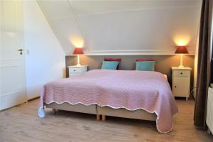een slaapkamer met een groot bed met 2 lampen bij Buitenplaats Villa 6-p in Callantsoog