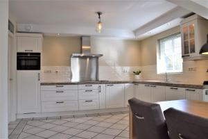 eine große Küche mit weißen Schränken und einem Tisch in der Unterkunft Buitenplaats Villa 6-p in Callantsoog