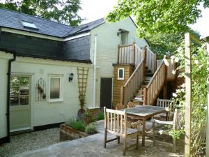 a patio with a table and a house with a staircase at Vinegar Hill Pottery in Lymington