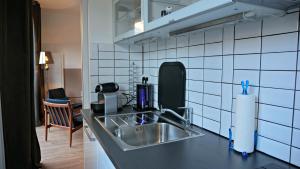 a kitchen with a stainless steel sink and white tiled walls at Little Suite - Constance in Lille