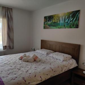 een bed met kussens en een schilderij aan de muur bij Guest House Šapina in Korenica