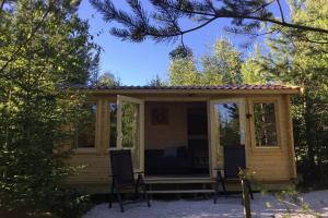 a log cabin with a porch and two chairs at Cozy Lodge near Brattforsheden nature reserve in Filipstad +15 photos