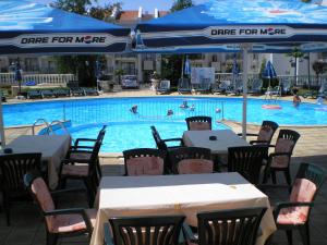 a pool with tables and umbrellas and people in the swimming pool at LAZUR 1, 2, 3, 4, 5 Apart Complex in Sveti Vlas