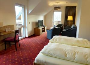 ein Hotelzimmer mit einem Bett, einem Schreibtisch und Stühlen in der Unterkunft Ferienhotel Wolfsmühle in Rodishain