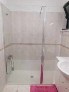 a shower with a glass door next to a sink at Penha House in Faro