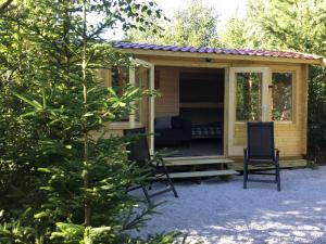 une petite cabine jaune avec une véranda et une chaise dans l'établissement Cozy Lodge near Brattforsheden nature reserve, à Filipstad