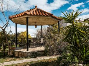a wooden gazebo with a table and chairs in a garden at Holiday villa with sea view in Paralia Avlidas in Dhílesi