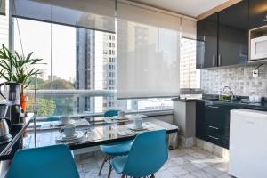 eine Küche mit blauen Stühlen und einem großen Fenster in der Unterkunft Seja Paulista Residence in São Paulo