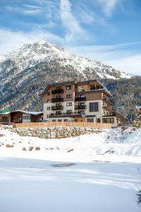 un grand bâtiment en face d'une montagne enneigée dans l'établissement Lakeside by A CASA, à Sölden