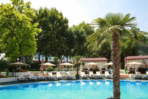 a palm tree next to a pool with chairs and umbrellas at Wyndham Tashkent in Tashkent