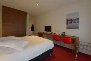 a hotel room with a bed and a desk and two chairs at Corbie Mol in Mol