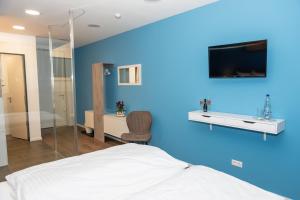 a blue room with a bed and a tv on a wall at LOK - Die Pension - Das Restaurant in Tessin