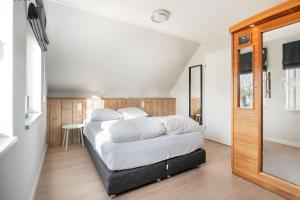 Schlafzimmer mit einem Bett mit weißer Bettwäsche und einem Spiegel in der Unterkunft Vakantiewoning Seaside in Oostkapelle