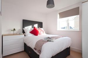a bedroom with a large bed with red pillows at Treeview Apartment- A lovely 2 bed apartment near Colchester North Station by Catchpole Stays in Colchester