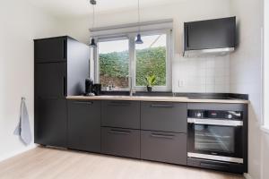 オーストカペッレにあるVakantiewoning Seaside, Burgvliet 11のキッチン(黒の電化製品付)、窓 +14枚の写真